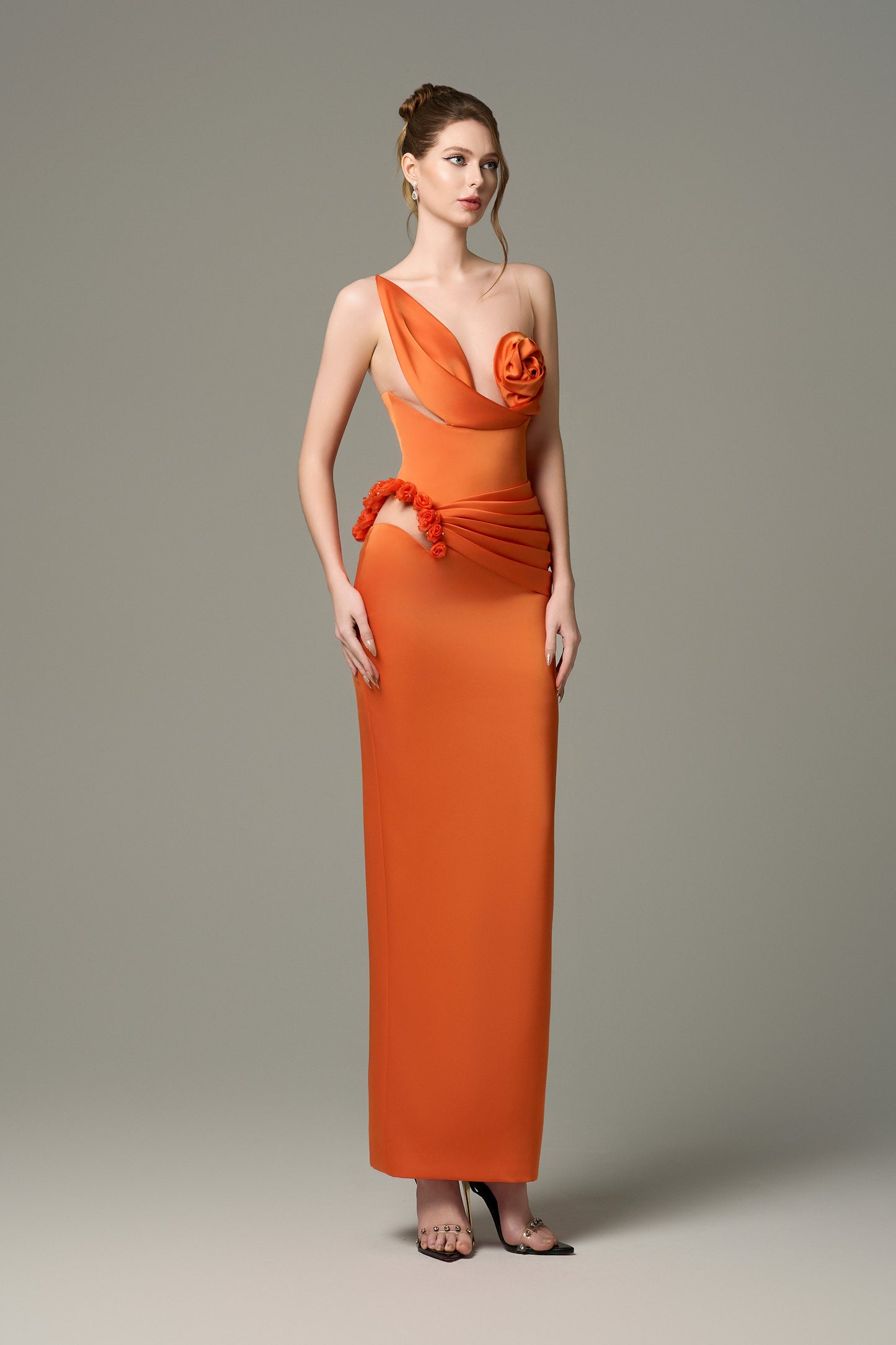 The Orange Silk Floral Bust Draped Maxi Dress features an asymmetrical floral bust and a high-slit skirt.