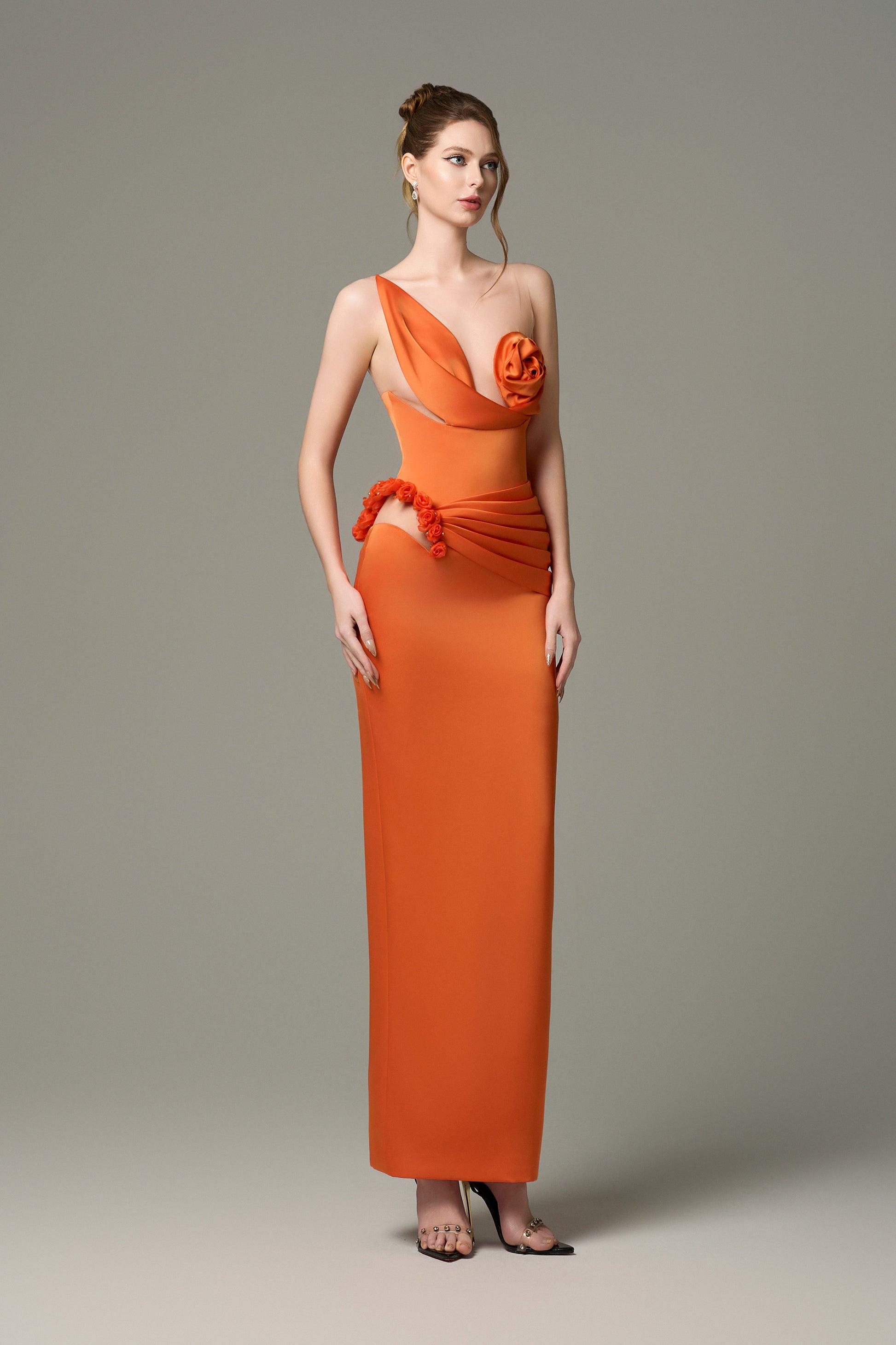 The Orange Silk Floral Bust Draped Maxi Dress features an asymmetrical floral bust and a high-slit skirt.