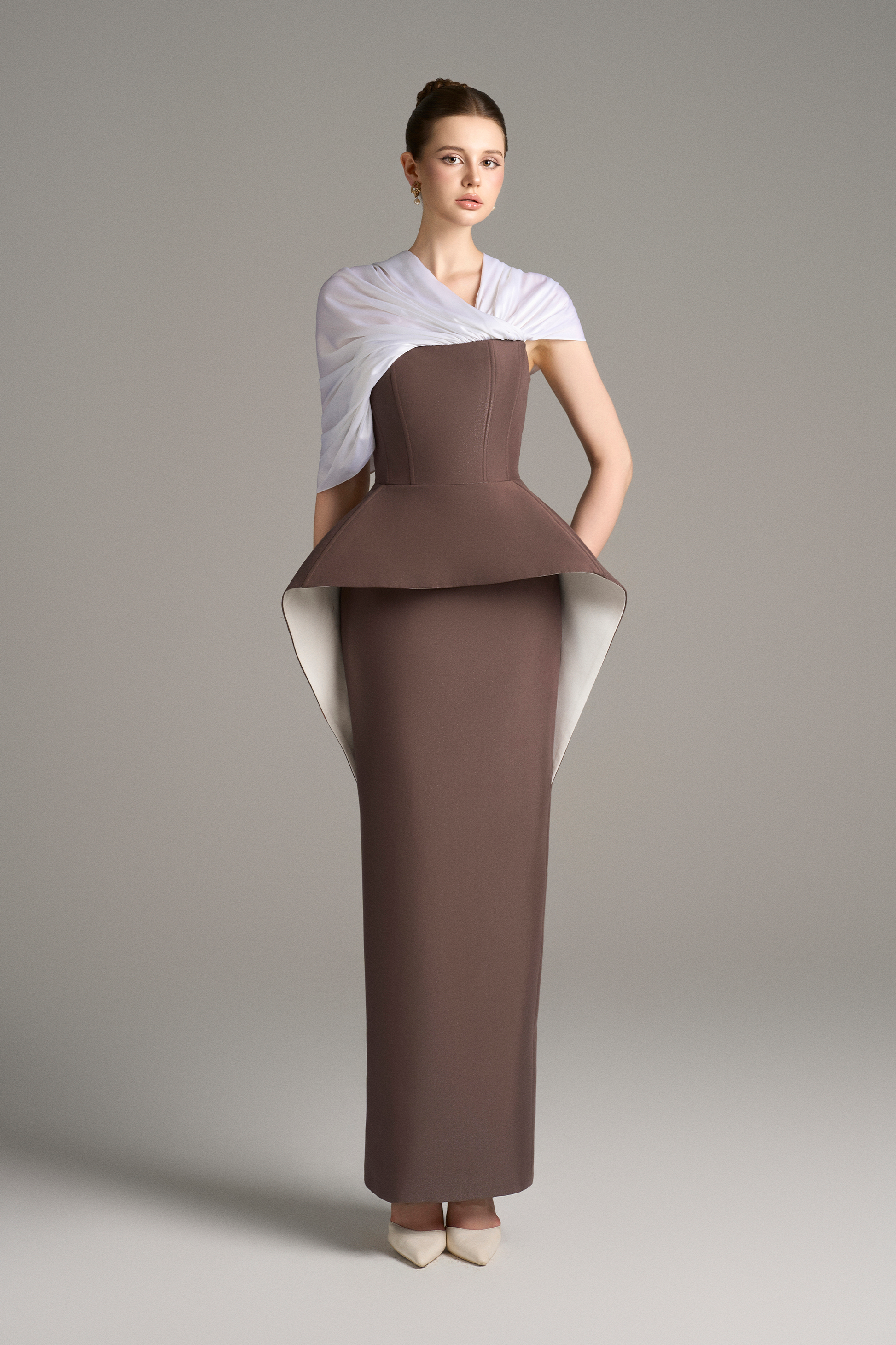Front view of strapless column gown with structured peplum detail and draped white shoulder wrap