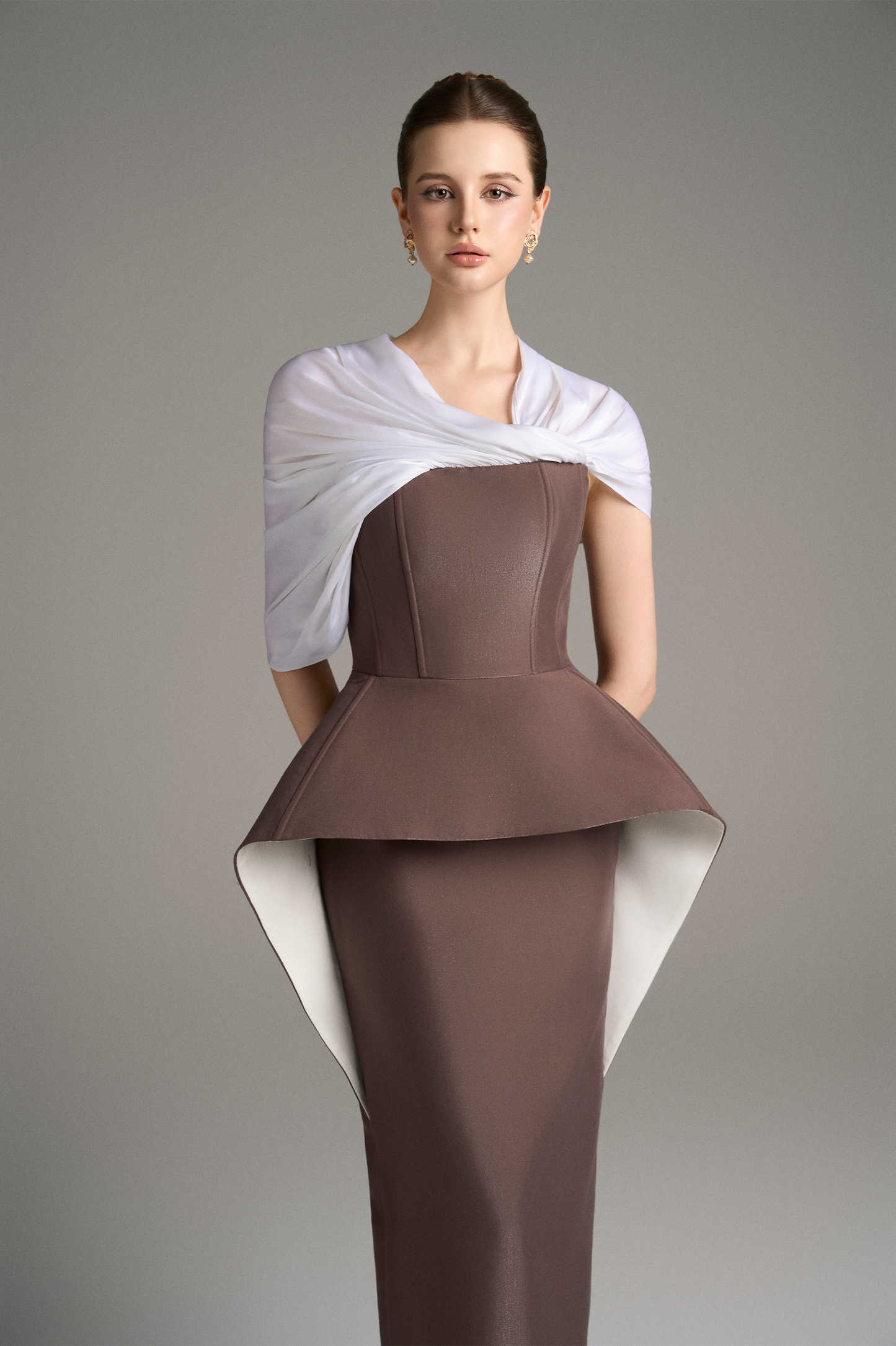 Close-up front view of strapless column gown with structured peplum detail and draped white shoulder wrap
