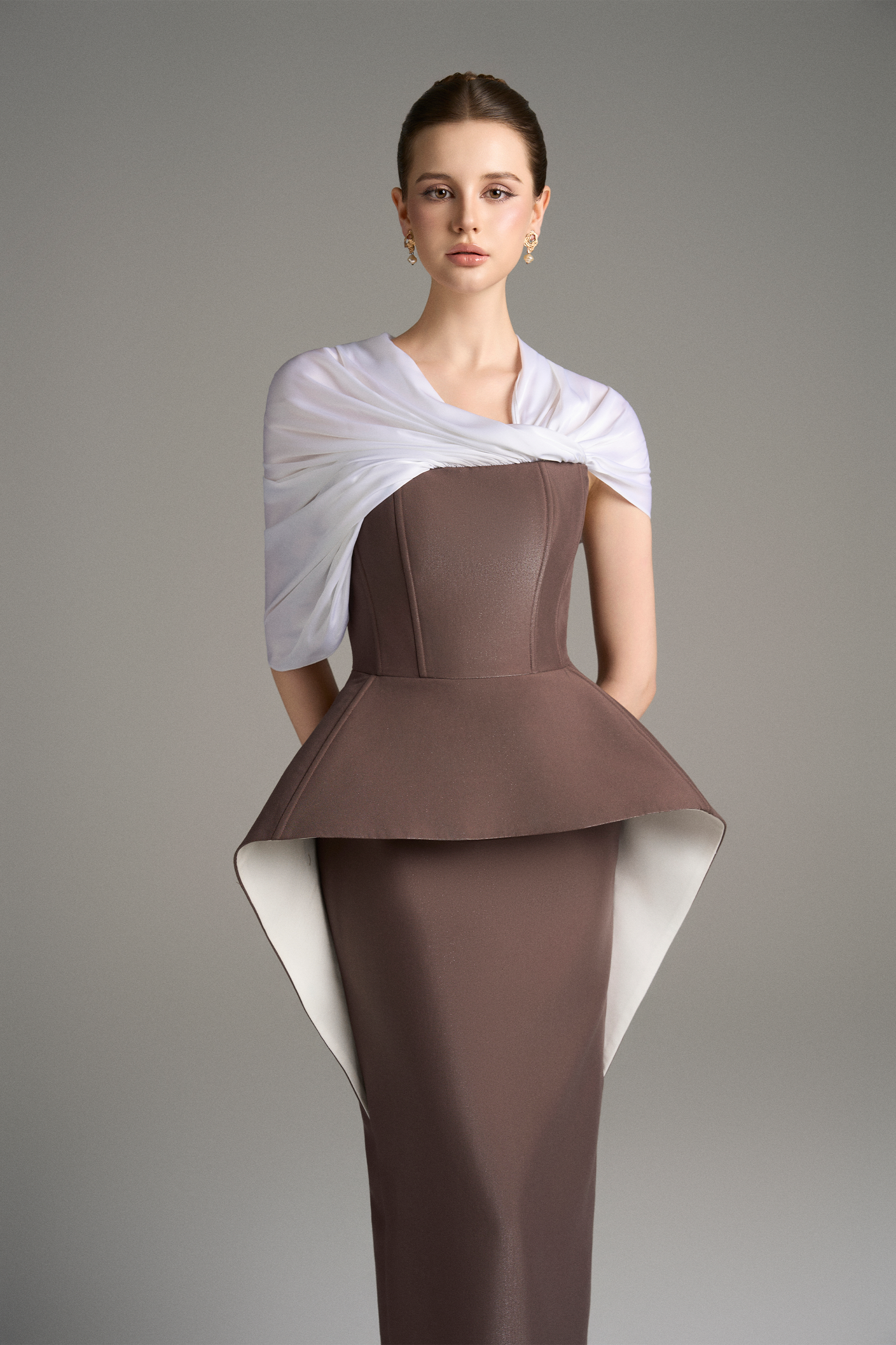 Close-up front view of strapless column gown with structured peplum detail and draped white shoulder wrap