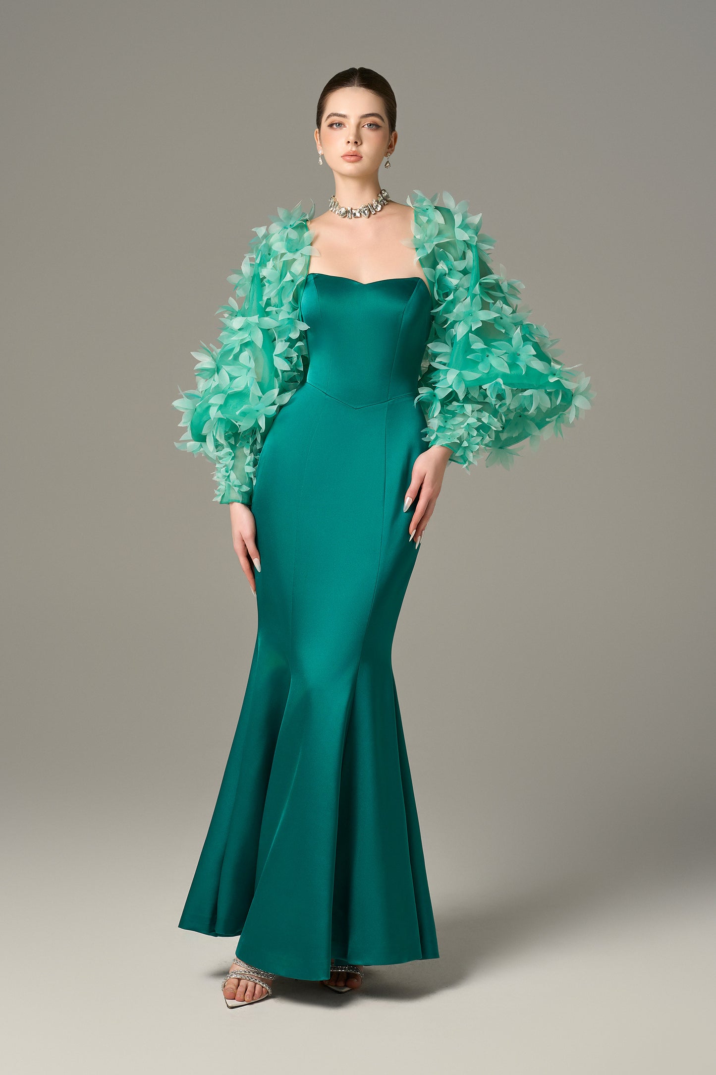 The Fishtail Gown stuns with emerald silk finish and a floral-embellished organza cape.