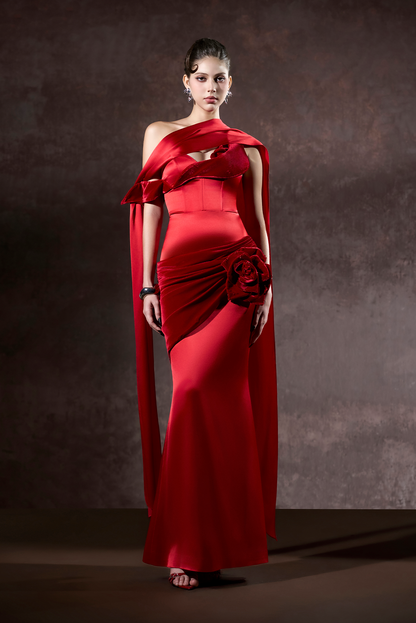 Woman wearing a red one-shoulder evening gown against a dark background