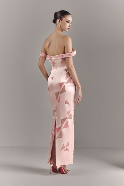 Woman wearing a pink off-shoulder evening gown with geometric pattern on a gray background