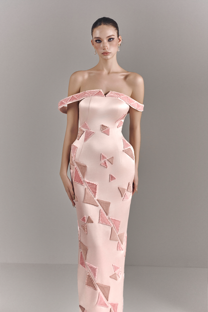Model wearing a pink off-shoulder dress with geometric pattern against a gray background