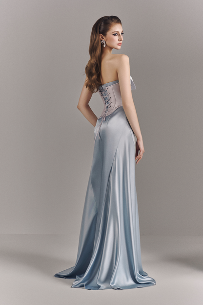 Woman wearing a strapless, floor-length evening gown with intricate detailing on a plain background