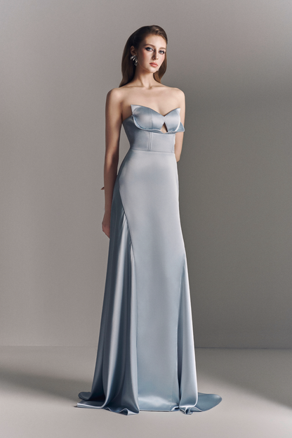 Woman wearing a strapless, floor-length light blue gown against a neutral background