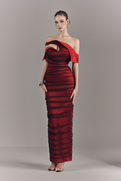 Woman wearing a red and black off-shoulder evening gown on a gray background