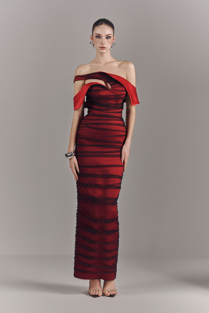 Woman wearing a red and black striped off-shoulder gown on a gray background