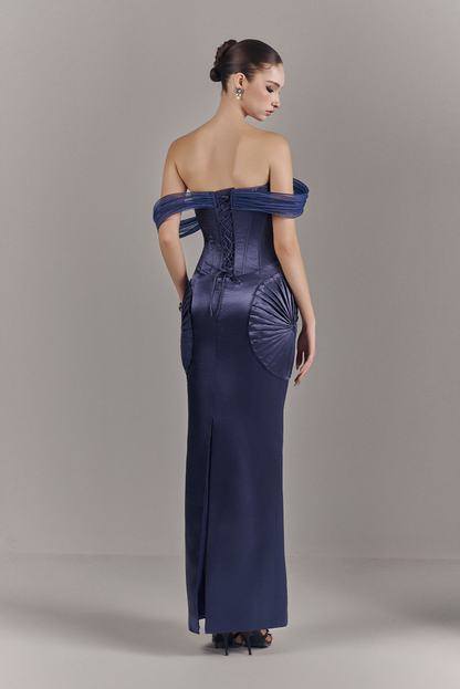 Woman wearing a long, off-shoulder blue dress against a plain background