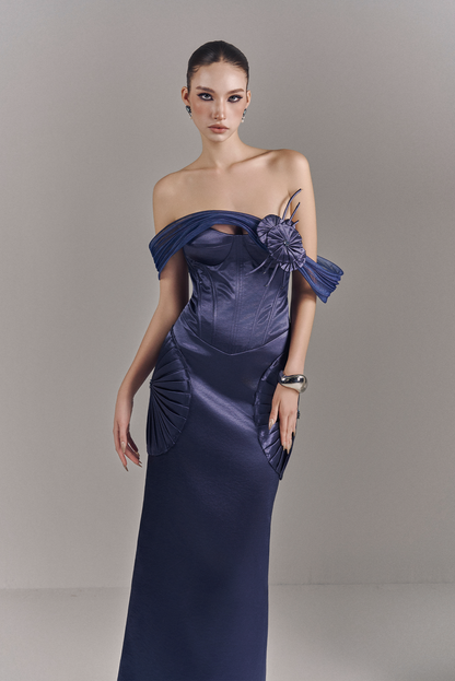 Woman wearing a blue evening gown with floral details on a gray background