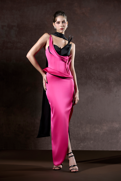Model wearing a pink evening gown with a black top against a dark background