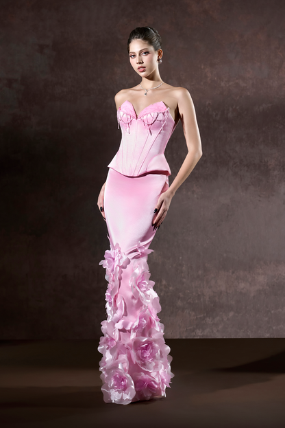Woman wearing a pink strapless gown with floral details on a dark background