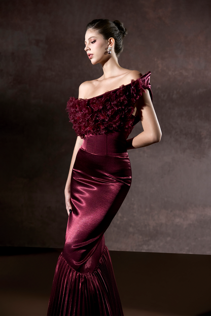 Woman wearing a burgundy evening gown against a dark background