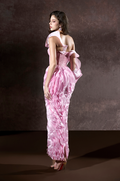 Woman in a pink evening gown with a bow detail on a dark background