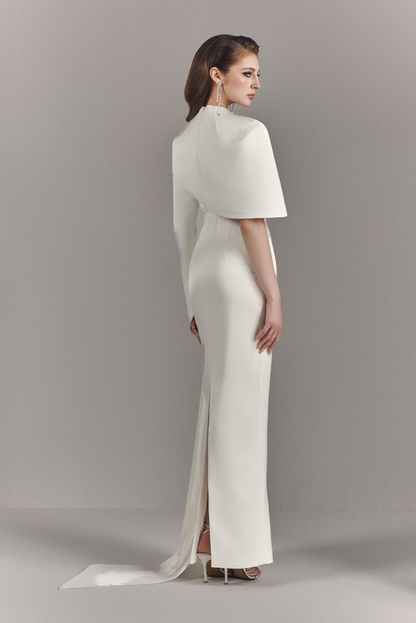 Woman wearing a white evening gown with a cape on a gray background