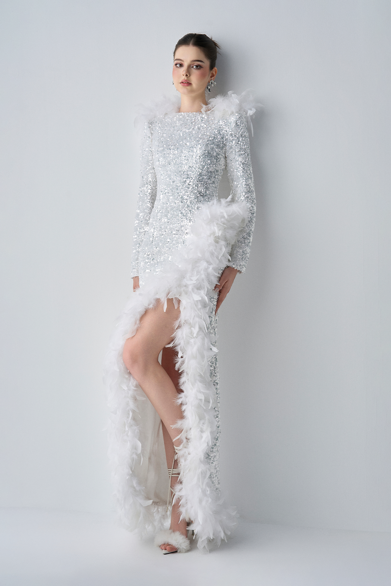 Woman wearing a white, feathered evening gown against a plain background