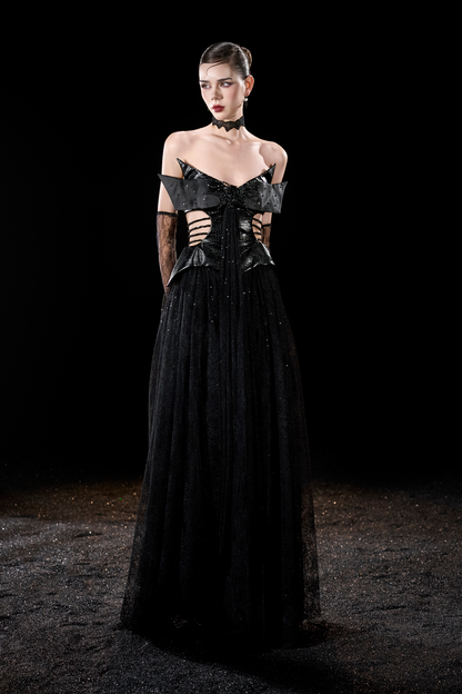 Model wearing a black evening gown with intricate detailing