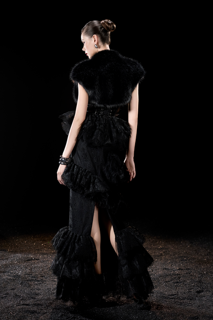 Woman wearing a black dress with ruffles and a fur collar 
