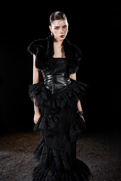 Model wearing a black dress with ruffled layers and fur accents