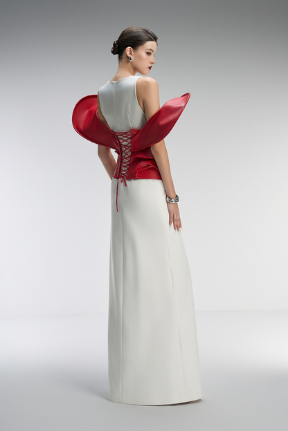 Woman wearing a white dress with a red bodice on a gray background