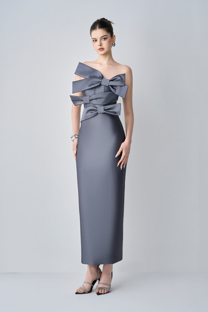 Woman wearing a gray gown with large bows on a white background