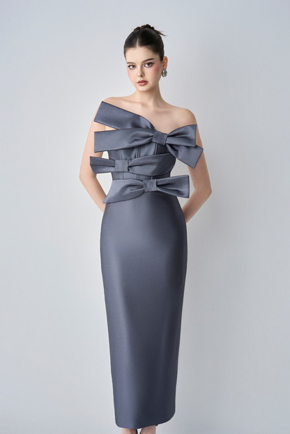 Woman wearing a gray dress with large bows on a white background