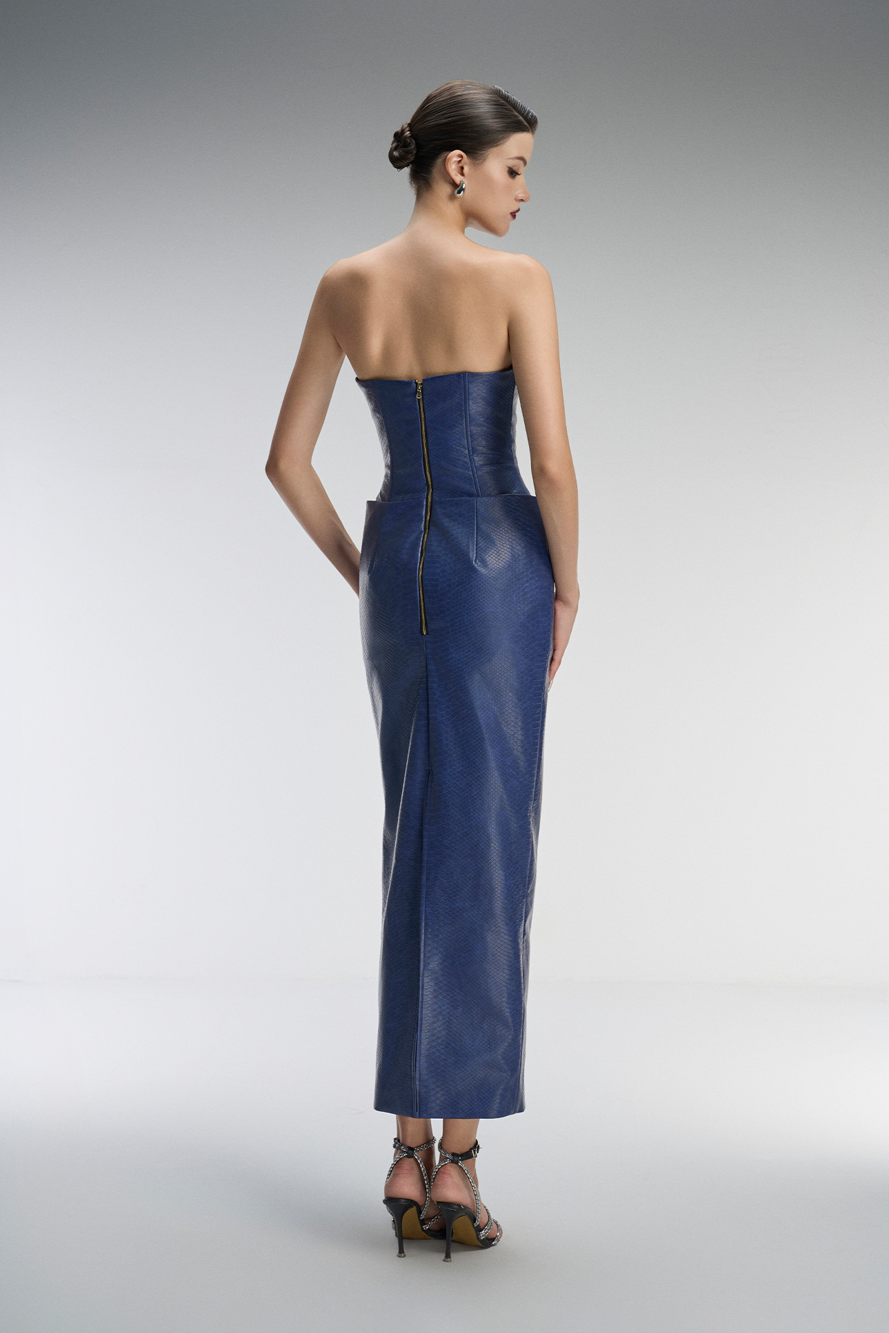 Woman wearing a strapless blue evening gown on a gray background