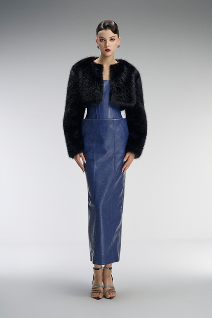 Woman wearing a black fur coat over a blue dress on a gray background