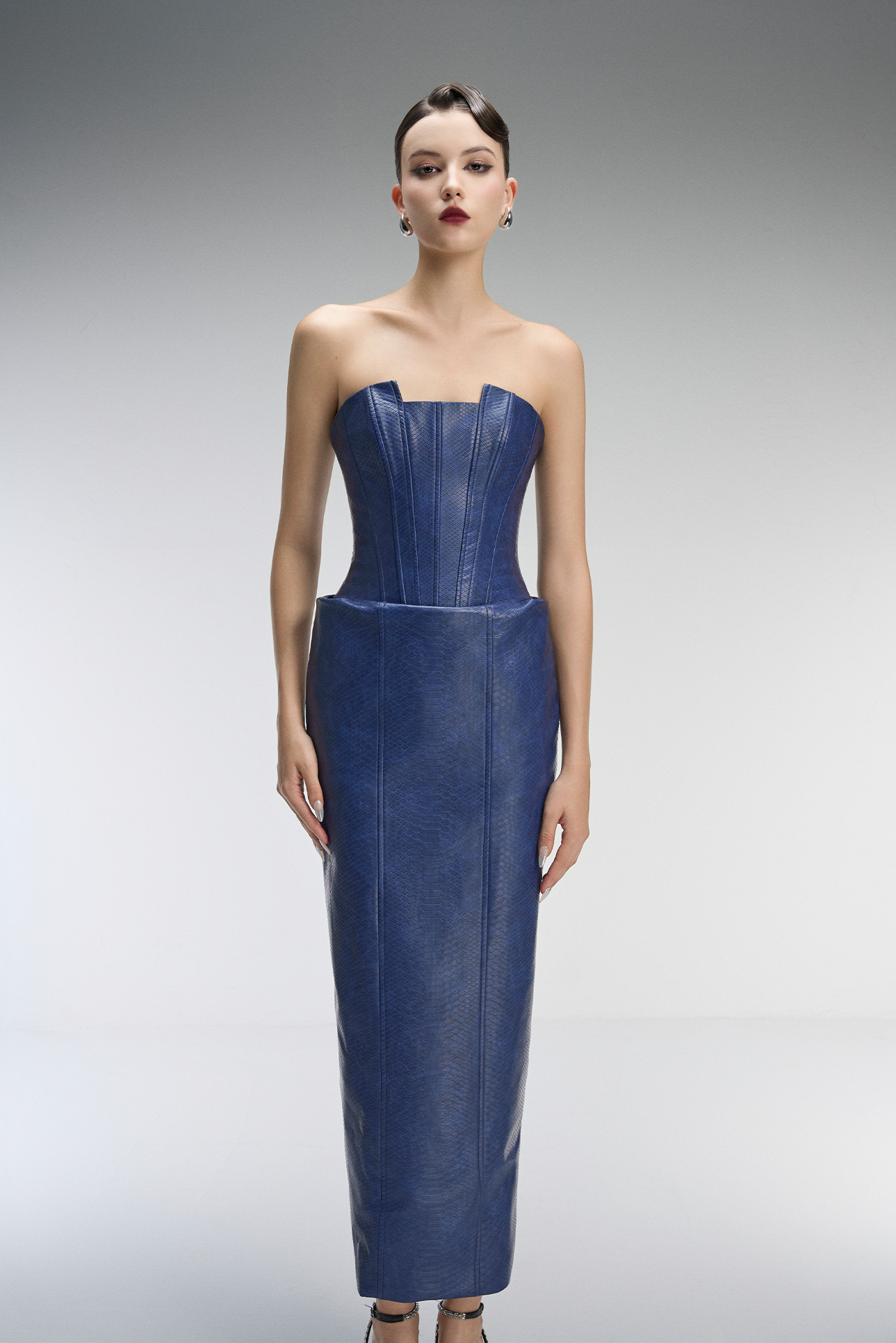 Woman wearing a strapless blue dress against a gray background