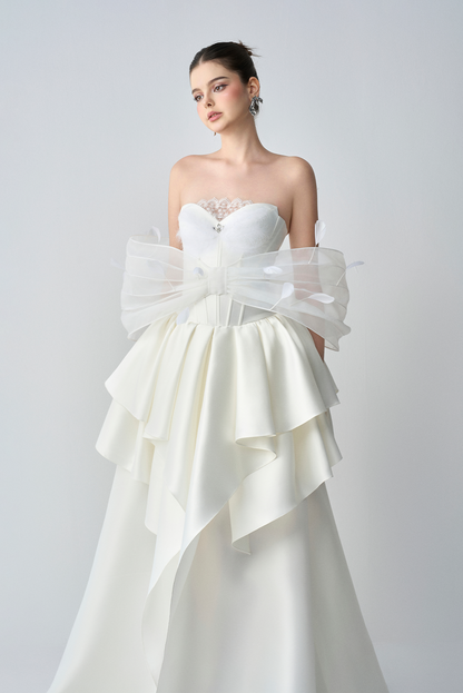 White strapless wedding dress with ruffled sleeves on a plain background