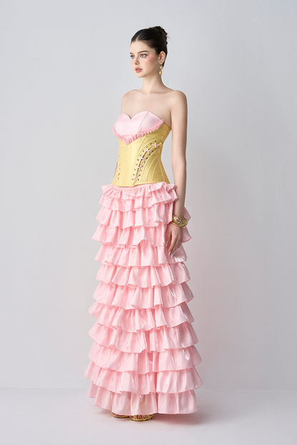Woman wearing a pink and yellow strapless dress with ruffled layers on a white background