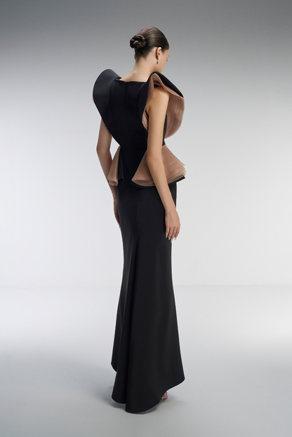 Woman wearing a unique black and brown dress on a gray background