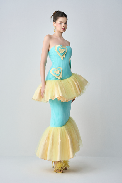 Woman wearing a blue and yellow dress with heart designs on a white background