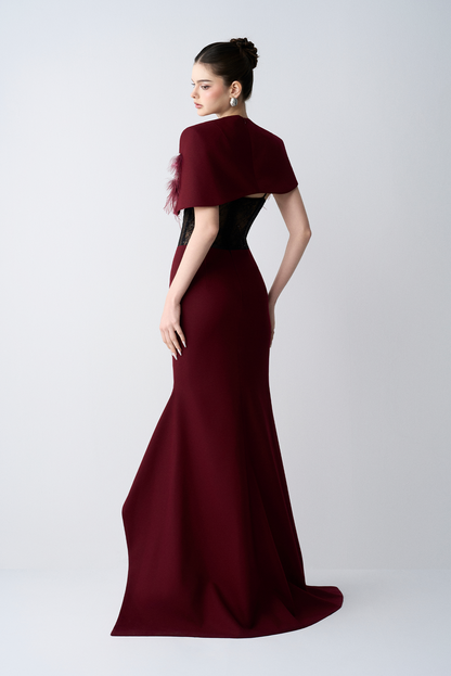 Woman wearing a burgundy evening gown with a fitted design on a white background