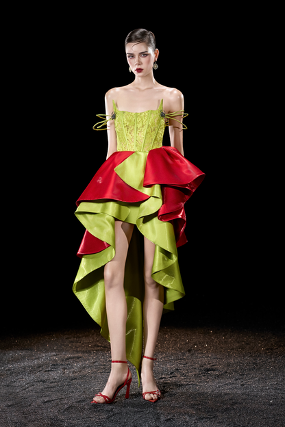 Model wearing a vibrant green and red dress with ruffled layers