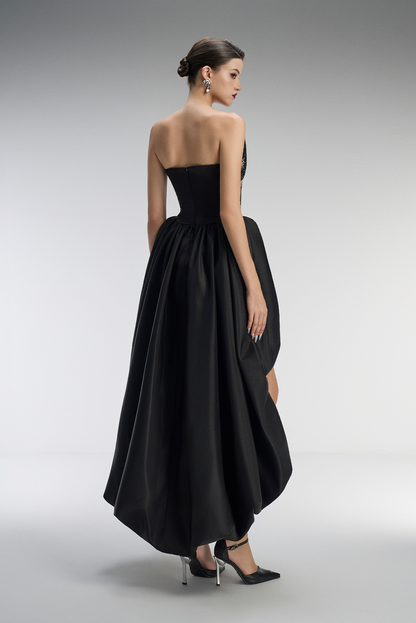 Black strapless gown with a high-low hem on a gray background