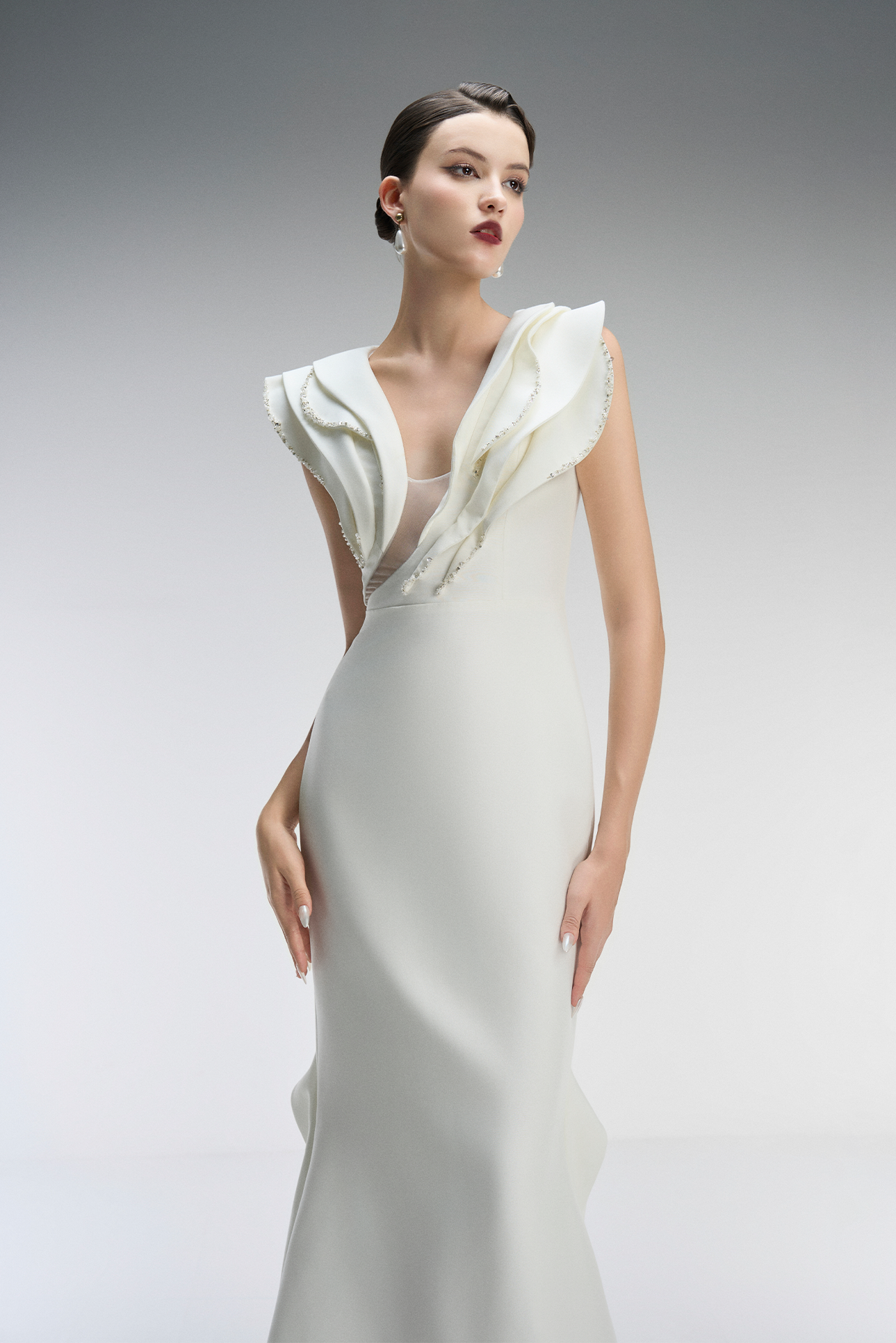 Model wearing a white dress with a draped neckline
