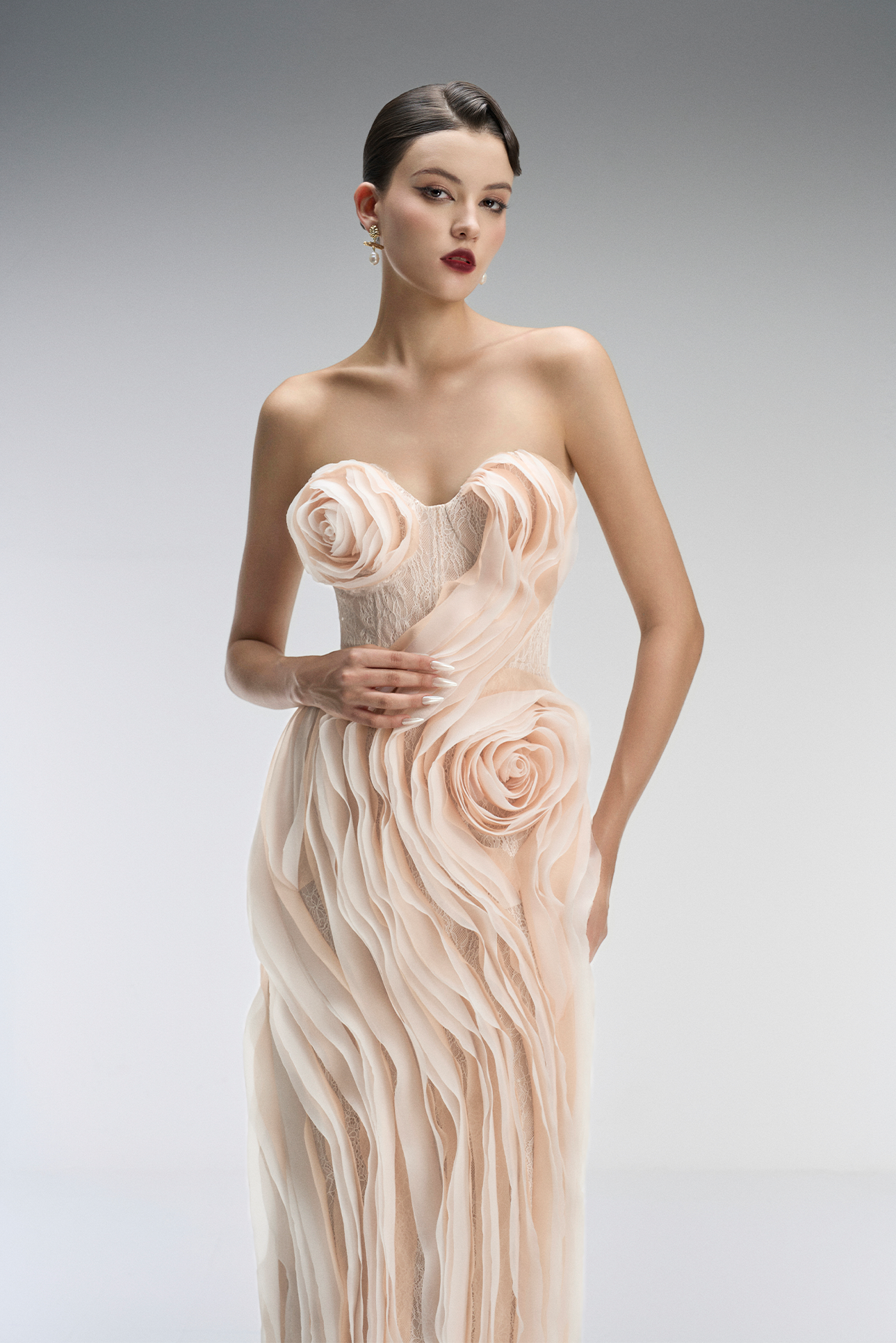 Woman wearing a strapless, floral gown against a plain background