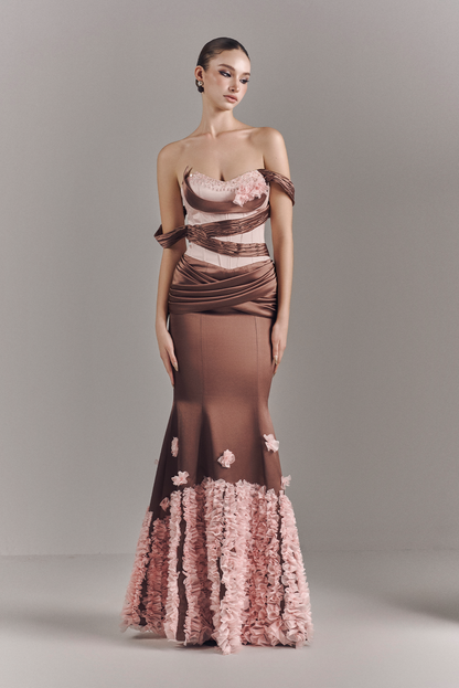 Woman wearing a strapless evening gown with floral details on a gray background