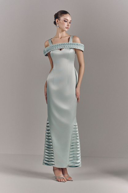 Woman wearing a light green off-shoulder evening gown against a gray background