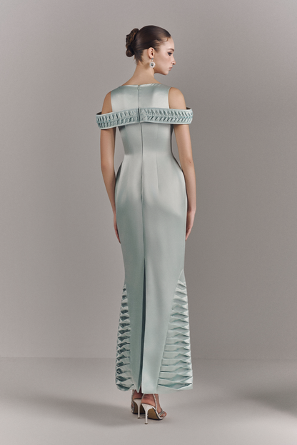 Woman wearing a light blue off-shoulder jumpsuit with ruffled details on a gray background