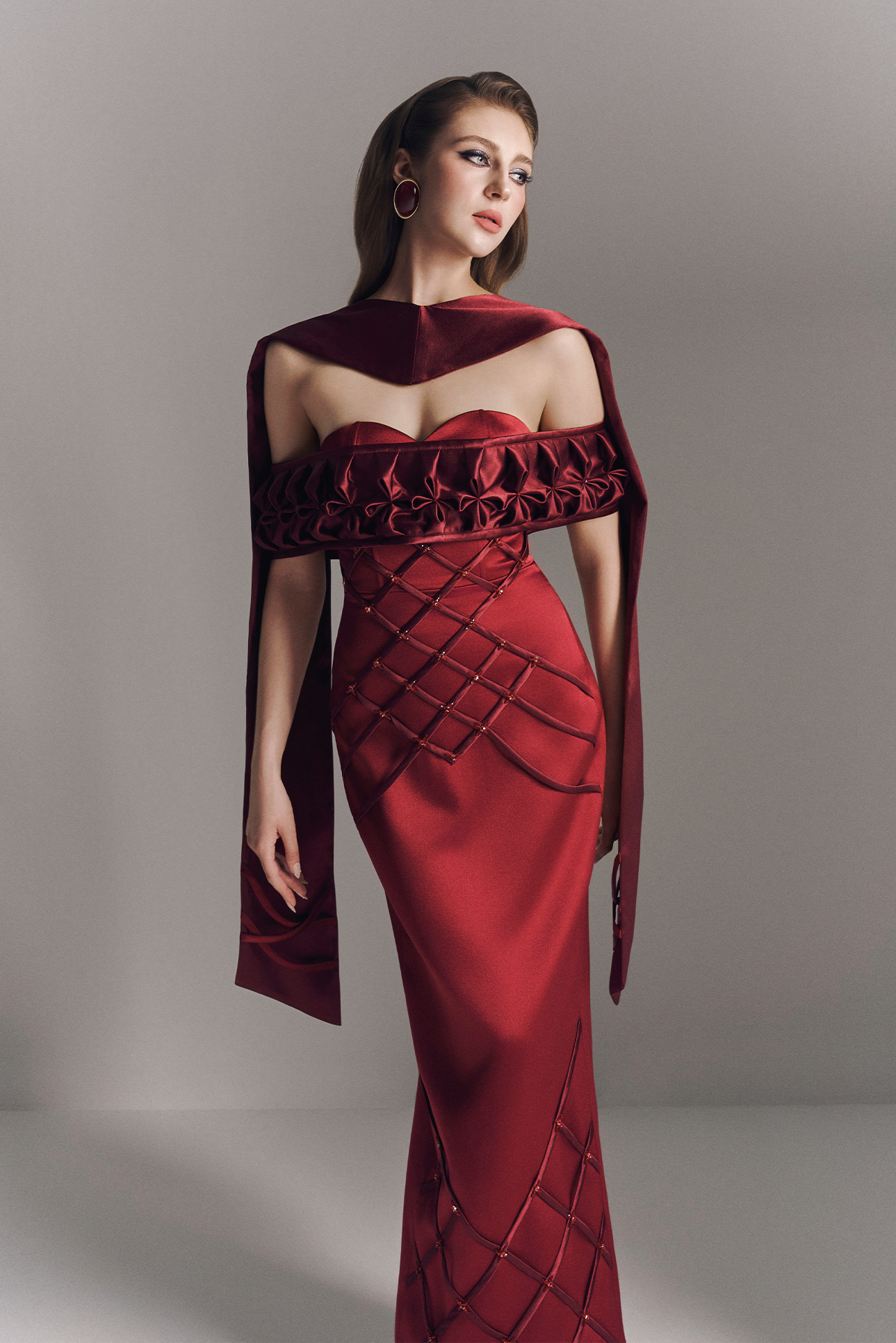 Red evening gown with intricate design on a gray background