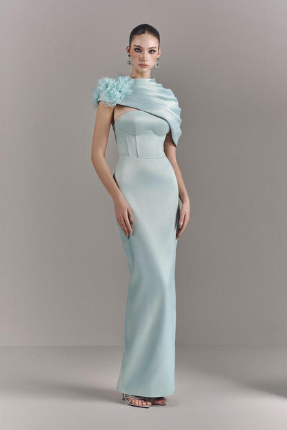 Woman wearing a light blue evening gown with a matching shawl on a gray background