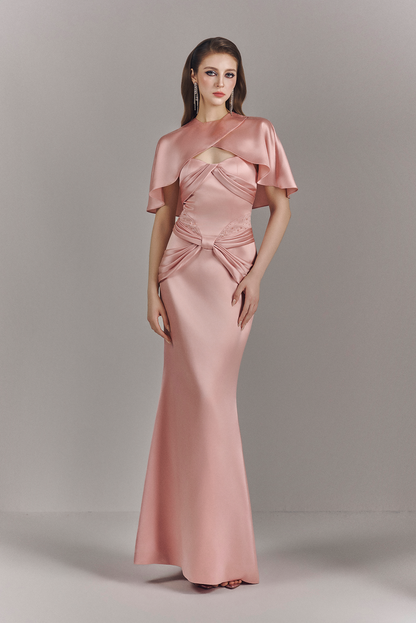 Woman wearing a pink evening gown with cape on a gray background