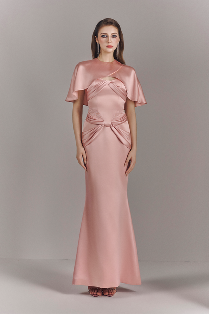 Woman wearing a pink evening gown with cape on a gray background