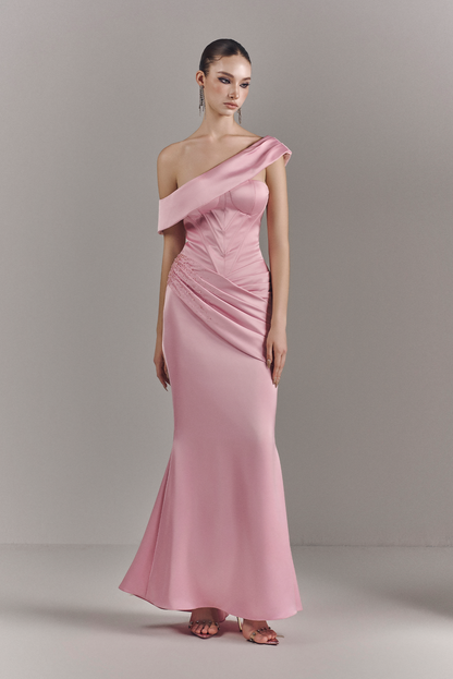 Woman wearing a pink one-shoulder evening gown against a plain background