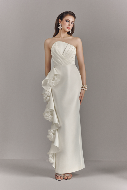 Woman wearing a strapless white gown with floral details on a gray background