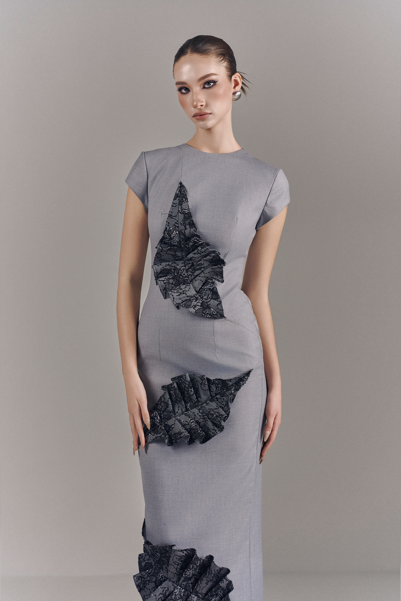 Woman wearing a gray dress with black geometric patterns on a plain background