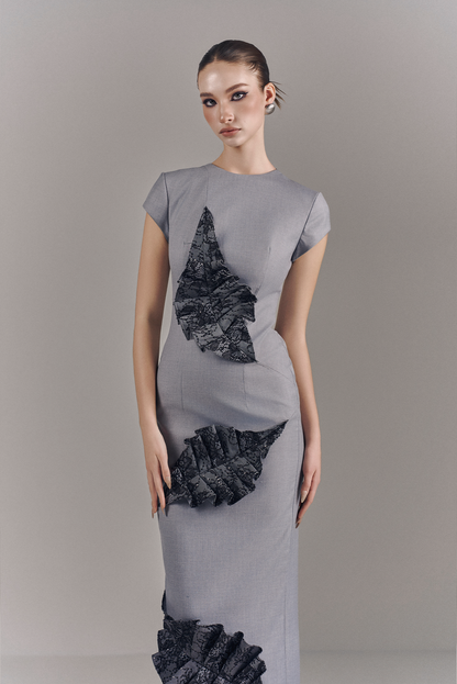 Woman wearing a gray dress with black geometric patterns on a plain background